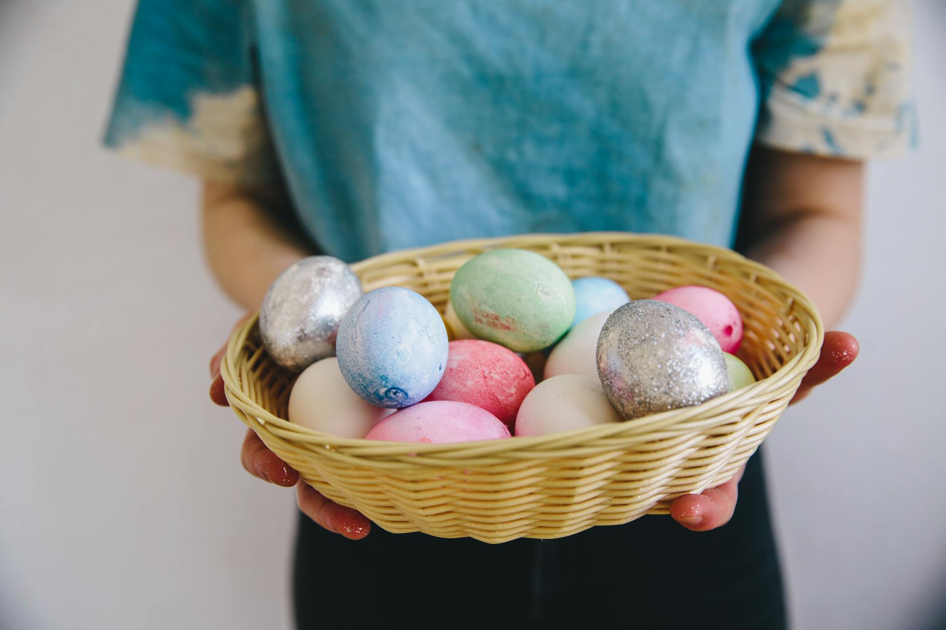 person holding a woven basket with easter eggs