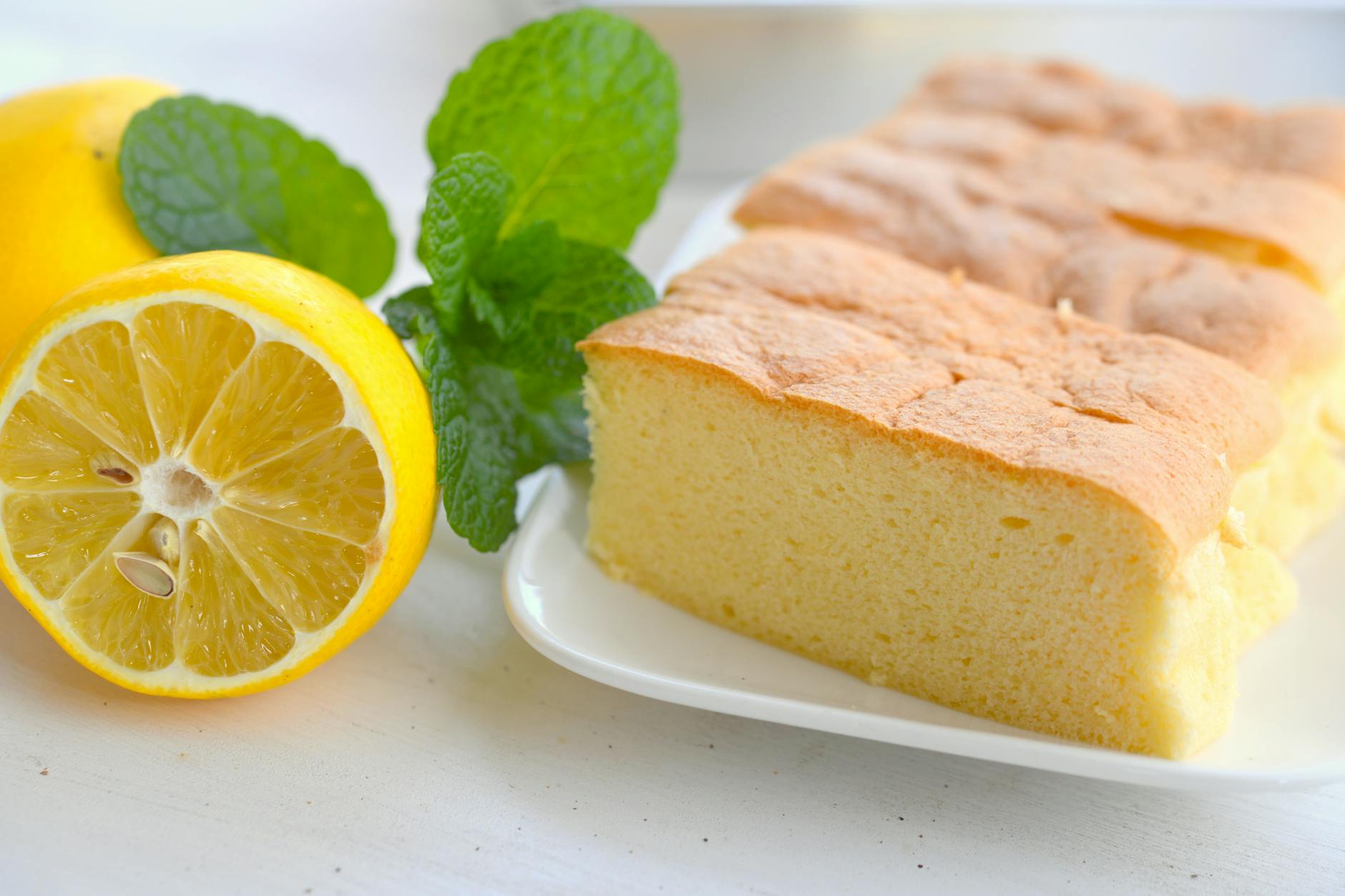 close up view of sliced sponge cake on a plate beside a lemon